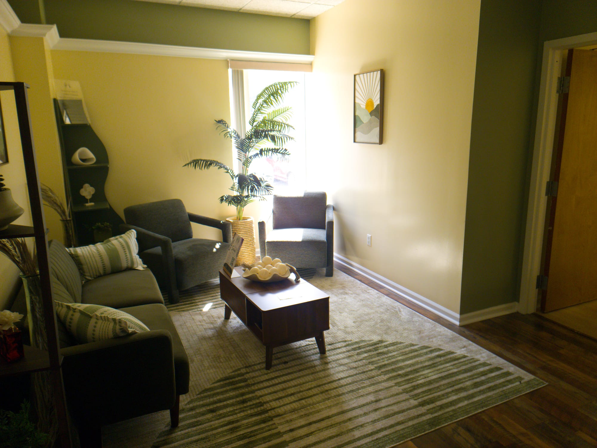Houda Holistics consultation lounge with sage walls, armchairs, and a palm